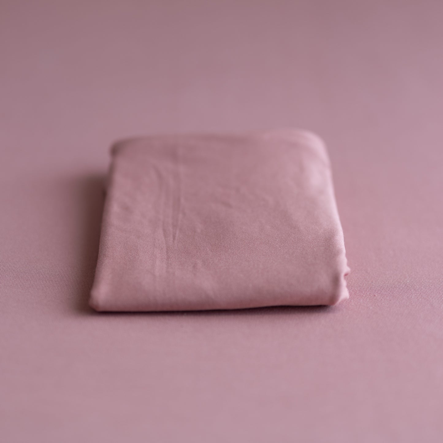 Folded pink fabric on a matching pink background